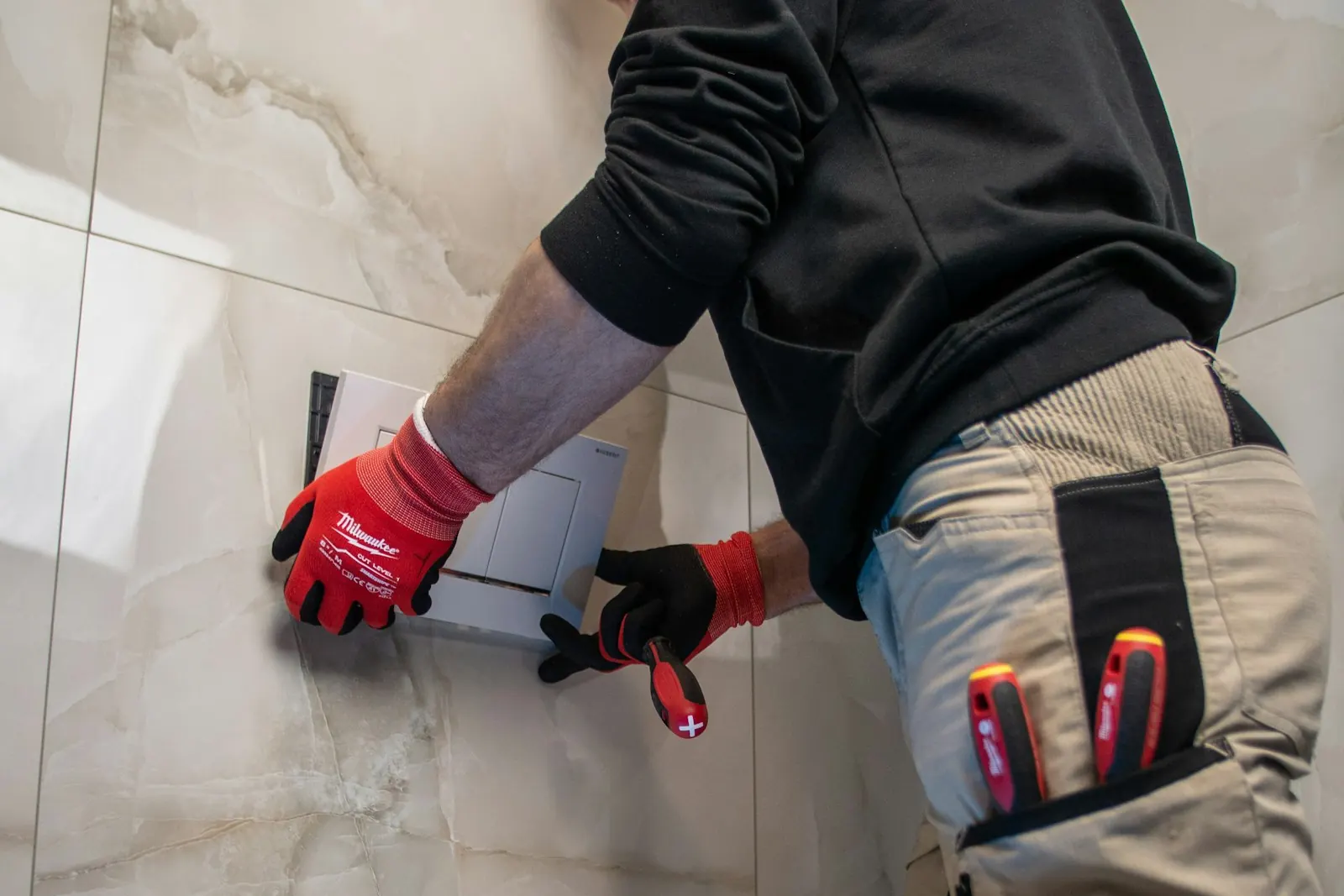 Technician in work gloves at a bathroom wall after a toilet overflow