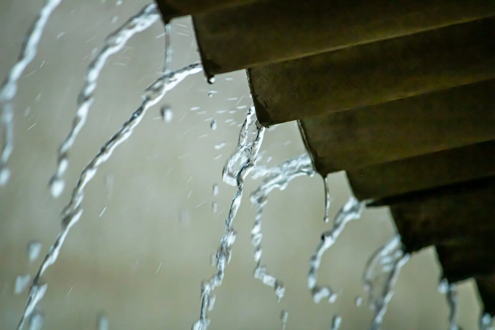 Heavy rain pouring off a roof edge during a storm